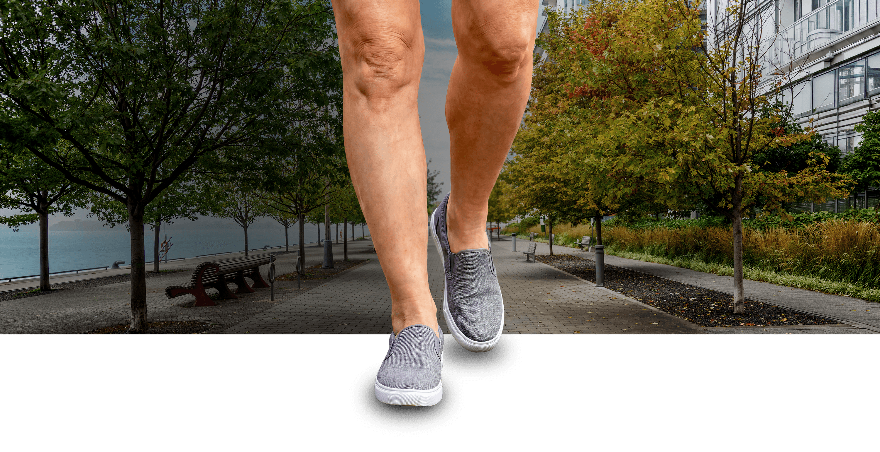 Une paire de jambes démesurément grandes, visibles de la mi-cuisse jusqu’aux pieds, marchant sur un trottoir.